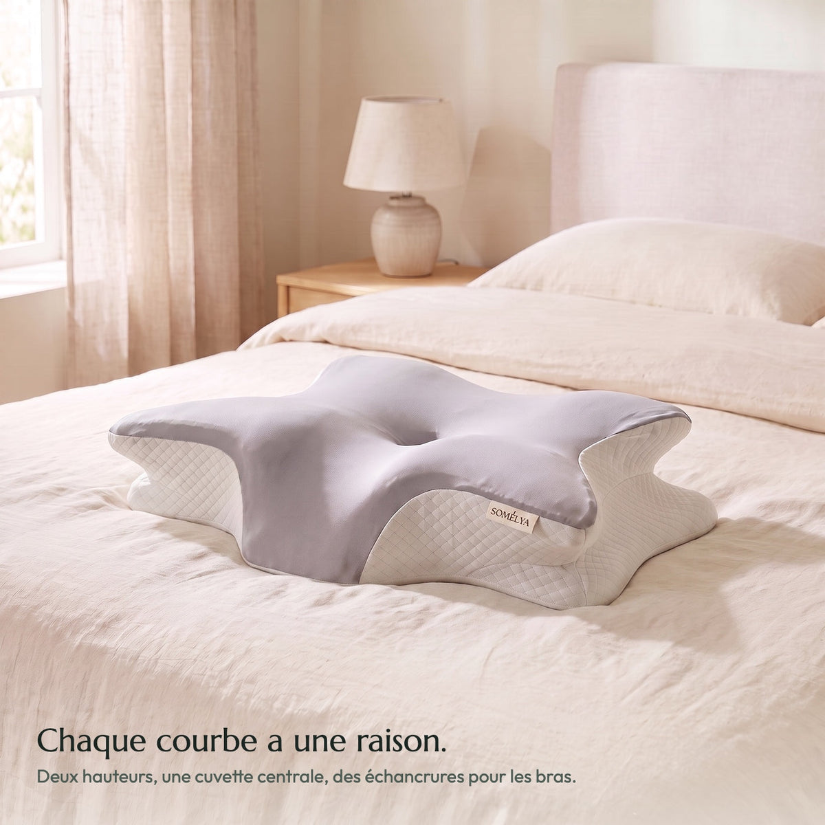 Oreiller ergonomique Somélya gris posé sur un lit en lin crème, ses quatre lobes et sa cuvette centrale visibles